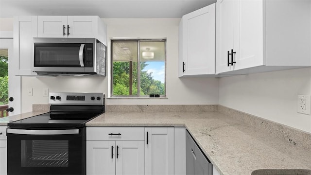 kitchen featuring stainless steel appliances, healthy amount of natural light, white cabinets, and light stone counters