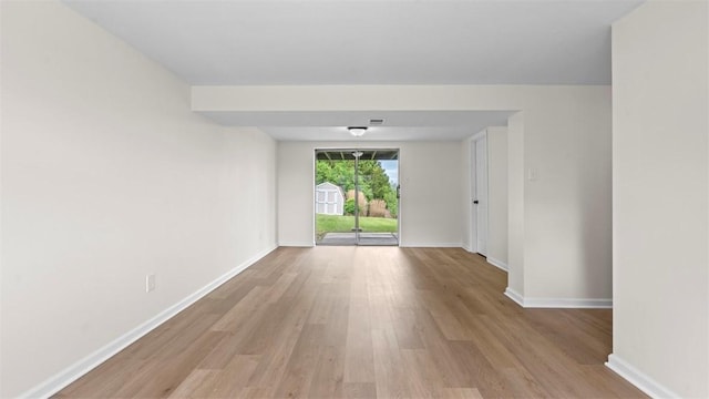 unfurnished room with light wood-type flooring and baseboards