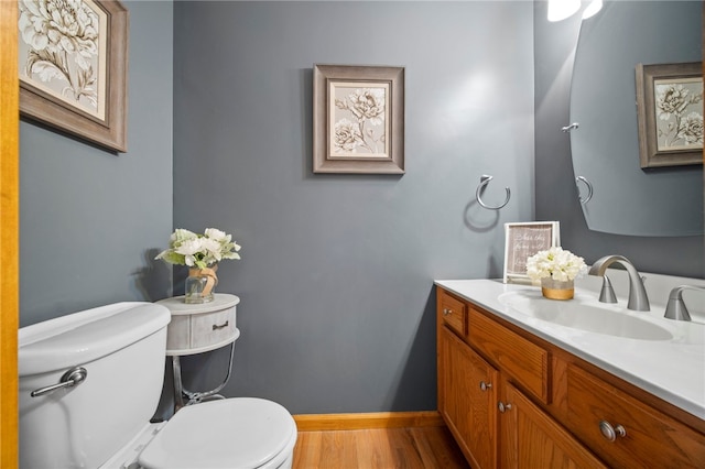 bathroom featuring toilet, wood finished floors, vanity, and baseboards