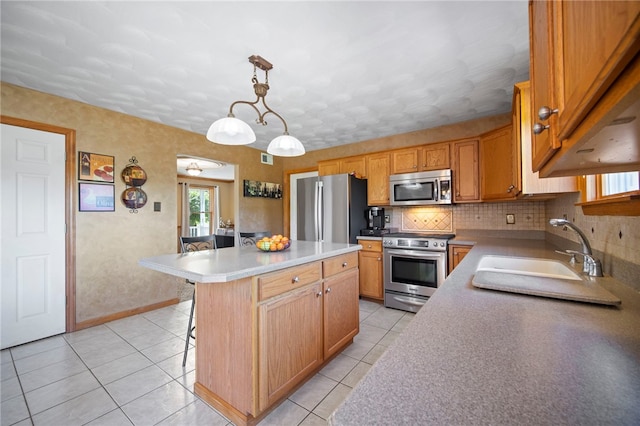 kitchen featuring appliances with stainless steel finishes, a sink, light tile patterned floors, a breakfast bar area, and a kitchen island