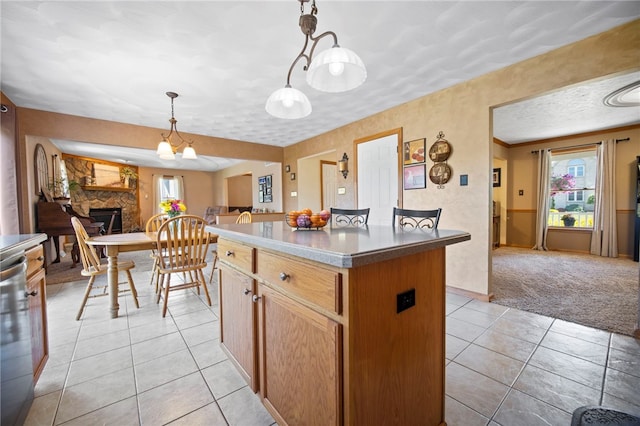 kitchen featuring a kitchen island, open floor plan, light tile patterned floors, a fireplace, and hanging light fixtures