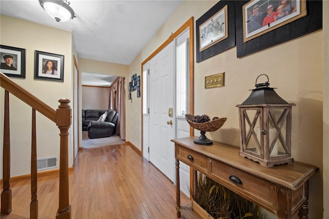 entrance foyer featuring light wood-style flooring, stairs, and baseboards