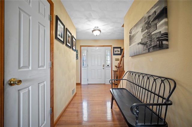 entryway featuring stairs, hardwood / wood-style flooring, and baseboards