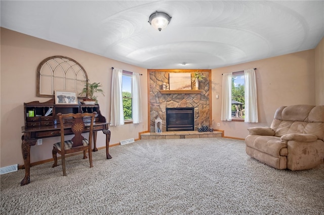 living room with baseboards, carpet, and a stone fireplace
