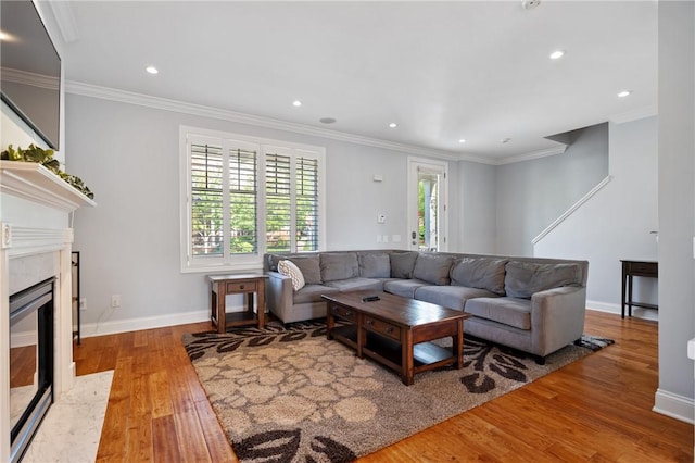 living room featuring wood finished floors, a high end fireplace, ornamental molding, recessed lighting, and baseboards