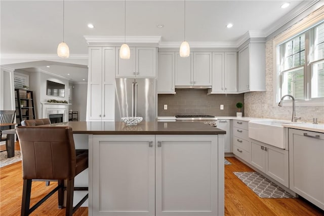 kitchen featuring stainless steel fridge, a sink, tasteful backsplash, a kitchen island, and crown molding