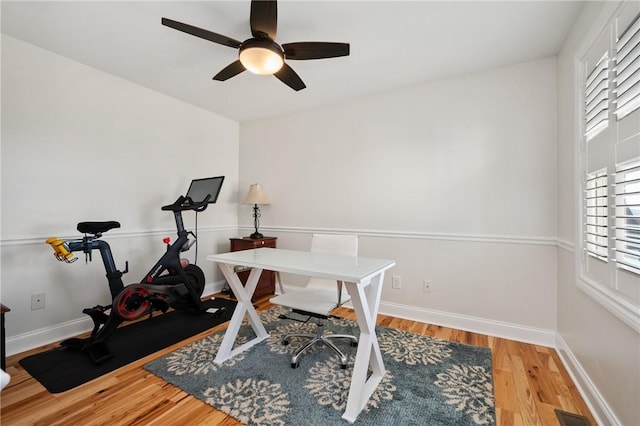 home office with wood finished floors, a ceiling fan, and baseboards