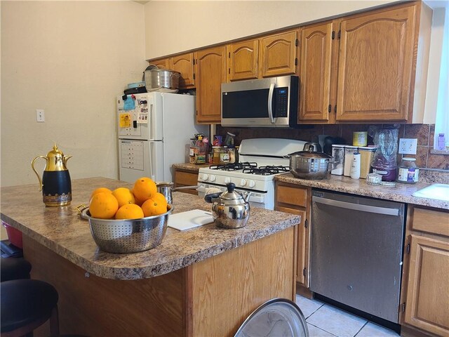 743 Taylor Ave, Avalon, PA 15202 - kitchen with appliances with stainless steel finishes, a breakfast bar area, light tile patterned floors, brown cabinets, and a sink