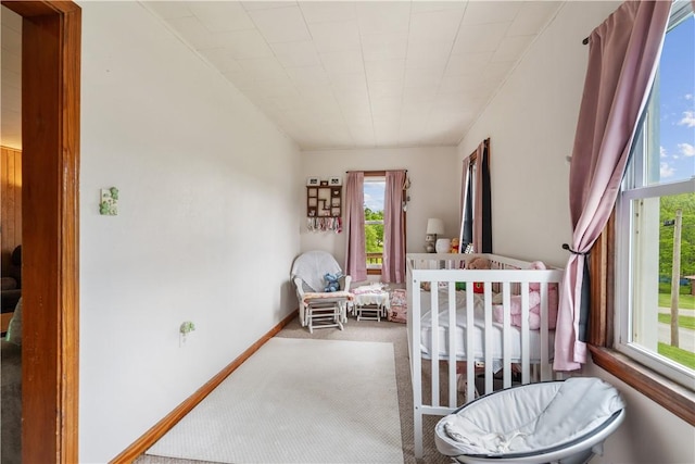 carpeted bedroom featuring multiple windows and baseboards
