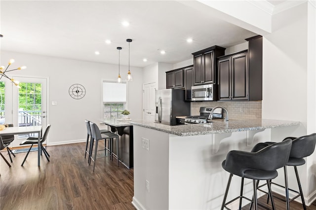128 Cole Dr, Robinson Twp Nwa, PA 15136 - kitchen featuring stainless steel appliances, dark wood finished floors, backsplash, light stone counters, and a breakfast bar area