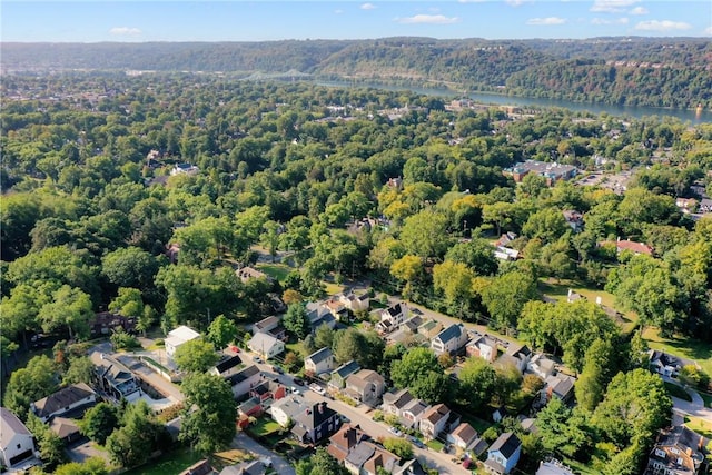 view of property location with a forest, a nearby body of water, and nearby suburban area