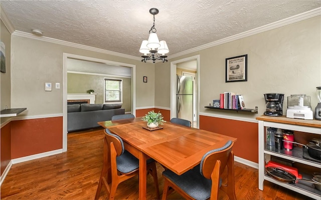 811 Jefferson Dr, Ross Twp, PA 15229 - dining room featuring wood finished floors, a chandelier, a fireplace, a textured ceiling, and crown molding