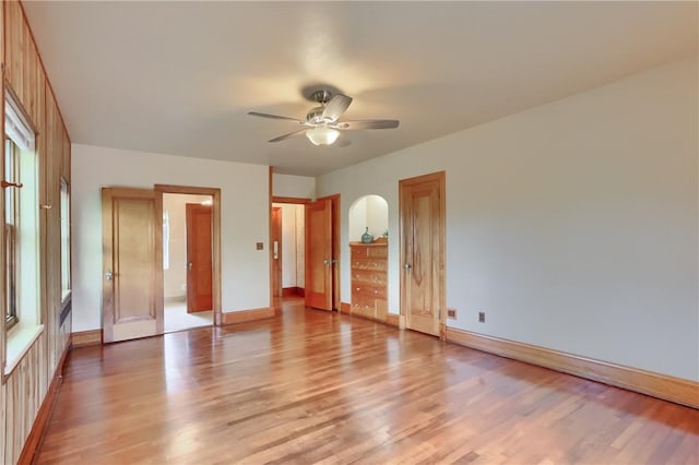 unfurnished bedroom with light wood finished floors, baseboards, multiple windows, and ceiling fan