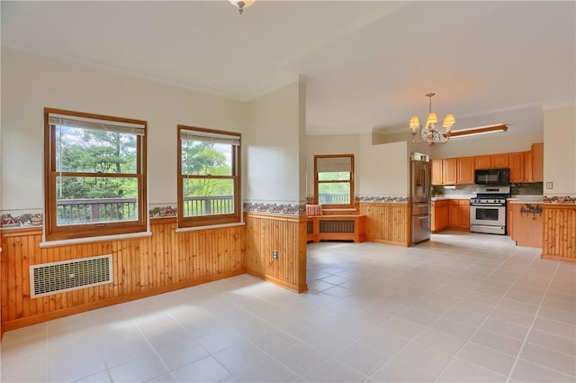 kitchen featuring stainless steel appliances, wainscoting, a chandelier, light countertops, and pendant lighting