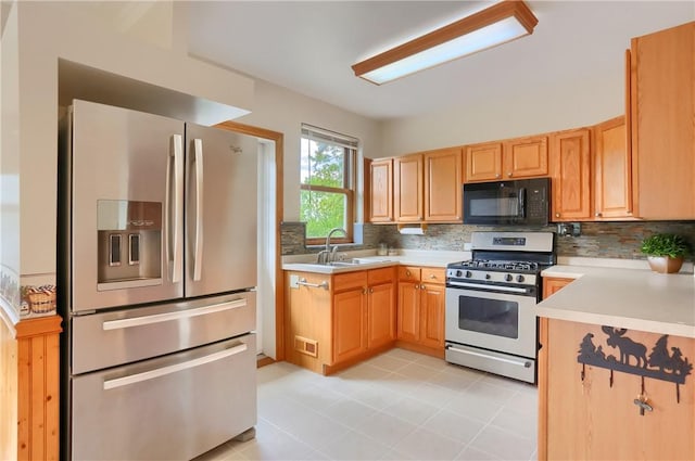 kitchen with appliances with stainless steel finishes, a sink, decorative backsplash, light countertops, and light tile patterned floors