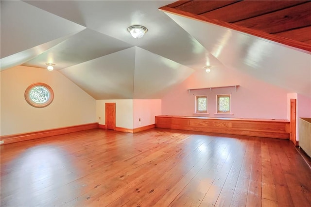 additional living space with wood-type flooring, vaulted ceiling, and baseboards