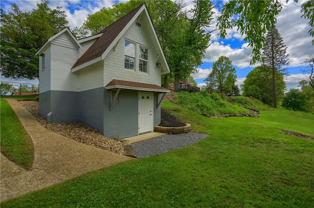 view of home's exterior featuring a yard, a shingled roof, and brick siding