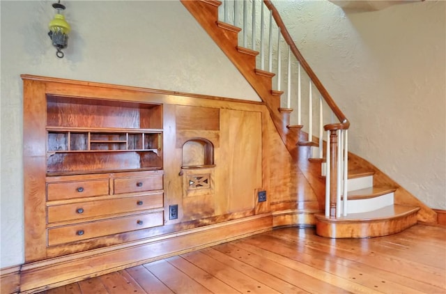 stairs featuring hardwood / wood-style floors and a textured wall