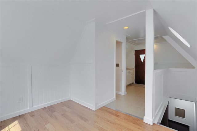 additional living space featuring light wood-type flooring, vaulted ceiling, recessed lighting, and a skylight