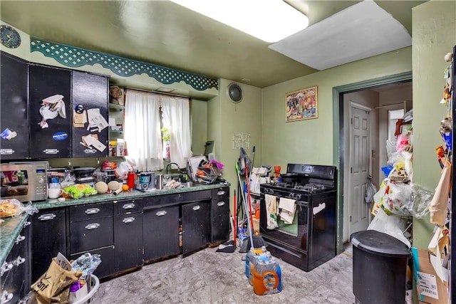 kitchen with black gas range, stainless steel microwave, dark cabinetry, and a sink
