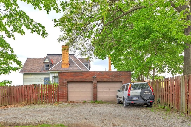 view of property exterior with a chimney, fence, and a garage