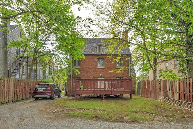 back of property featuring fence, brick siding, and a deck