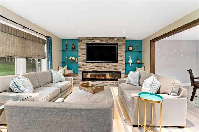 living area with wood finished floors, a stone fireplace, and recessed lighting