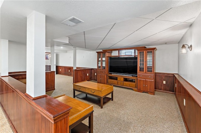 living room with wainscoting, carpet, wood walls, and a drop ceiling
