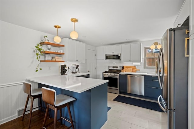 665 Dunster St, Brookline, PA 15226 - kitchen with appliances with stainless steel finishes, a peninsula, backsplash, white cabinets, and light countertops