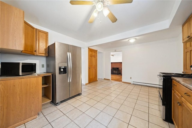kitchen featuring stainless steel appliances, a fireplace, ceiling fan, baseboard heating, and light tile patterned floors