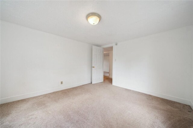 unfurnished room featuring light colored carpet and baseboards
