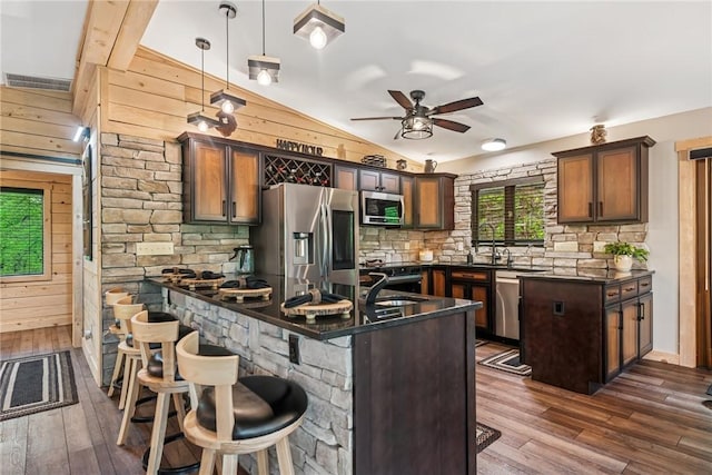 133 Imperial Rd, Hidden Valley, PA 15502 - kitchen featuring stainless steel appliances, dark countertops, wood walls, lofted ceiling, and a ceiling fan