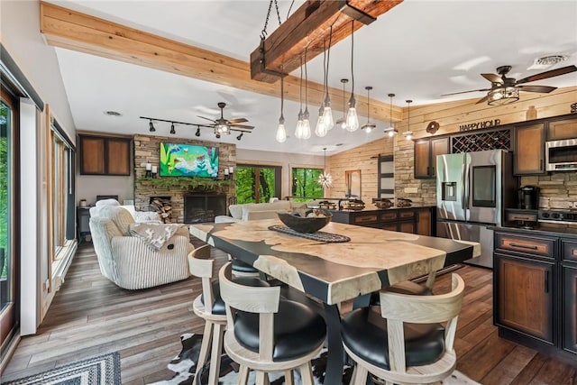 133 Imperial Rd, Hidden Valley, PA 15502 - dining room featuring ceiling fan, a stone fireplace, dark wood-style flooring, beam ceiling, and rail lighting