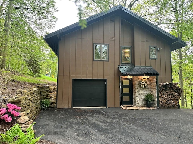 133 Imperial Rd, Hidden Valley, PA 15502 - view of front facade featuring a garage, asphalt driveway, board and batten siding, a standing seam roof, and a metal roof