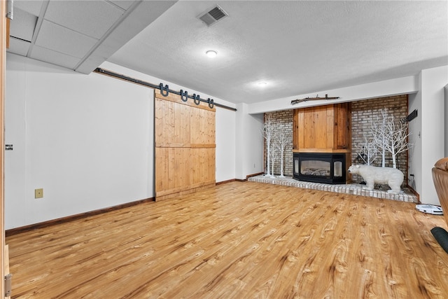 844 Old Millcreek Rd, Hookstown, PA 15050 - unfurnished living room featuring a barn door, wood finished floors, baseboards, a fireplace, and a textured ceiling