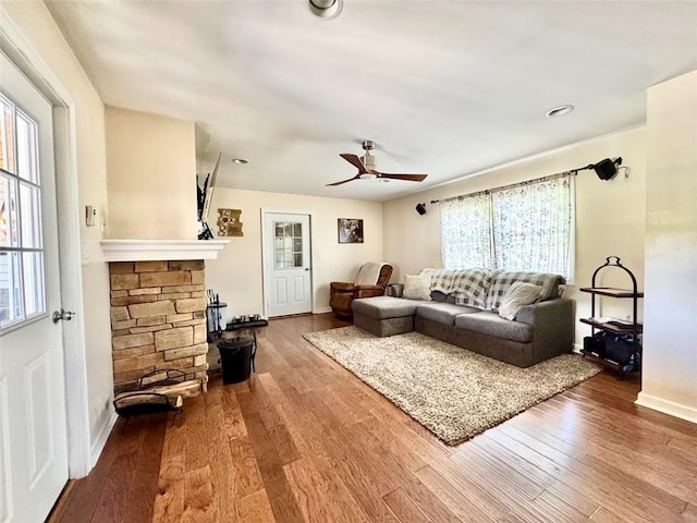 living area featuring wood finished floors, a ceiling fan, baseboards, and a fireplace