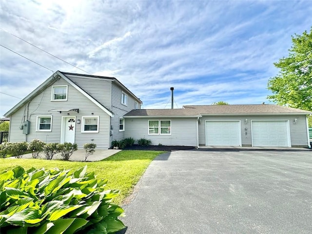 view of front of house with asphalt driveway, a front lawn, and an attached garage
