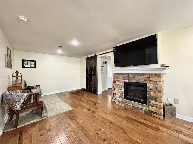 living area with a barn door, hardwood / wood-style flooring, baseboards, and a fireplace
