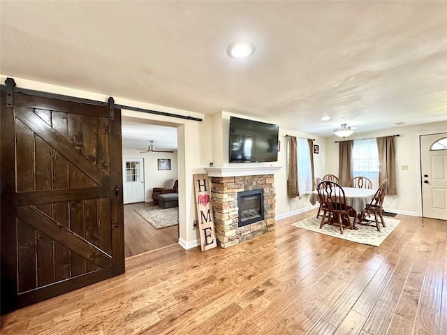 dining room featuring a barn door, light wood-style floors, baseboards, and a fireplace