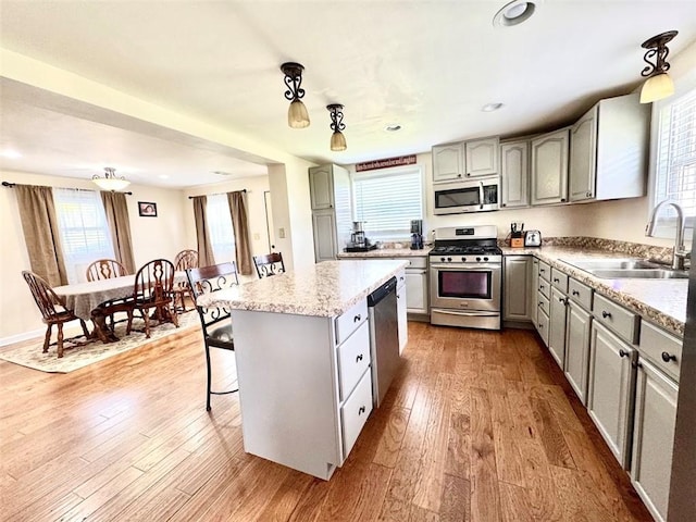 kitchen with stainless steel appliances, a sink, gray cabinetry, wood finished floors, and recessed lighting