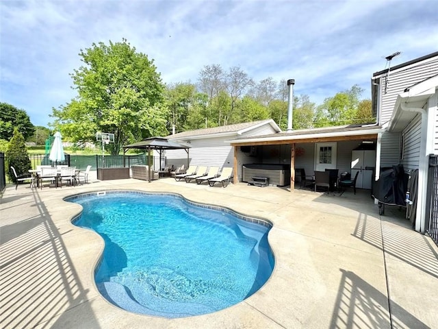 view of swimming pool with a hot tub, a gazebo, a patio, fence, and view of wooded area