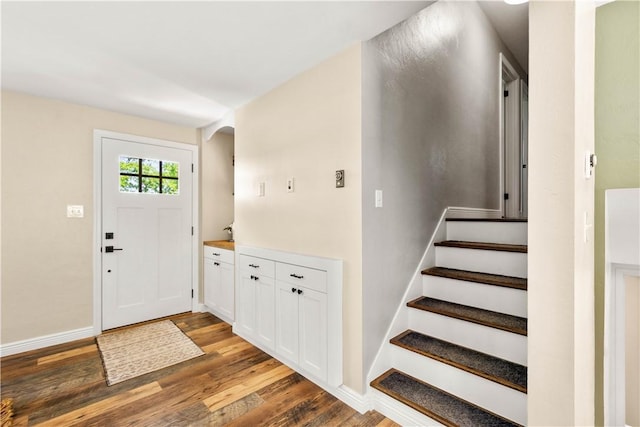 entryway with wood finished floors, stairway, arched walkways, and baseboards