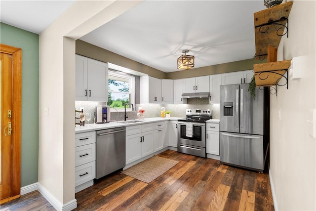 kitchen with appliances with stainless steel finishes, a sink, under cabinet range hood, tasteful backsplash, and light countertops