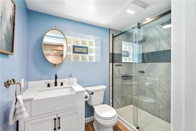 bathroom featuring toilet, a shower stall, vanity, and wood finished floors