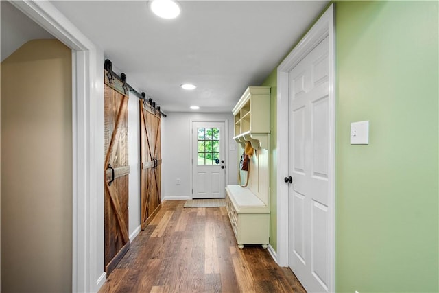 doorway to outside with a barn door, dark wood-style flooring, recessed lighting, and baseboards