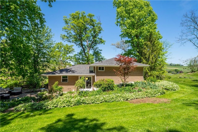 rear view of house featuring a yard, brick siding, and an outdoor hangout area