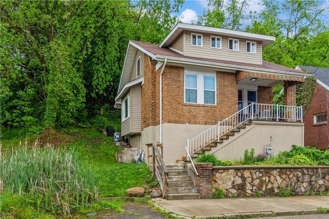 view of front of house featuring stairs, brick siding, and a porch
