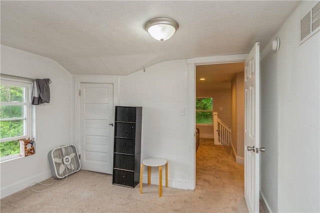 spare room featuring carpet, vaulted ceiling, plenty of natural light, baseboards, and a smoke detector