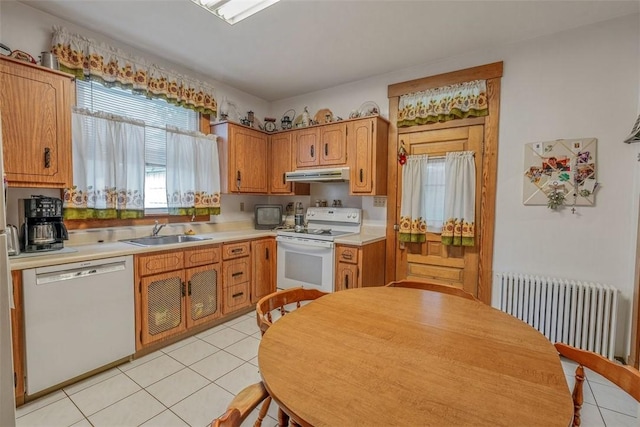 kitchen with white appliances, radiator, under cabinet range hood, a sink, and light tile patterned floors