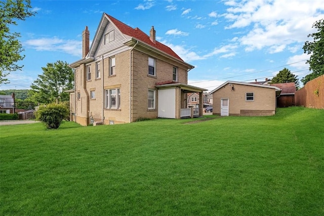 back of property featuring a chimney, a lawn, and brick siding